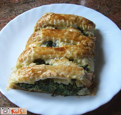 Pripravljen špinačni zavitek z gobami na pekaču, postrežen na krožniku