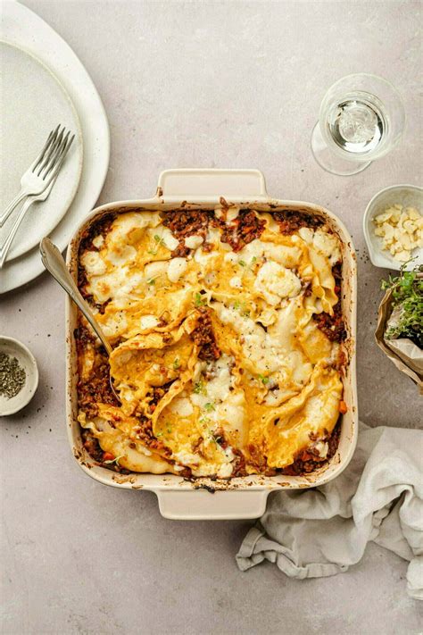 Pekač polnjenih testenin z bučnim nadevom in bolognese omako, posutih z naribanim sirom, pred peko v pečici.