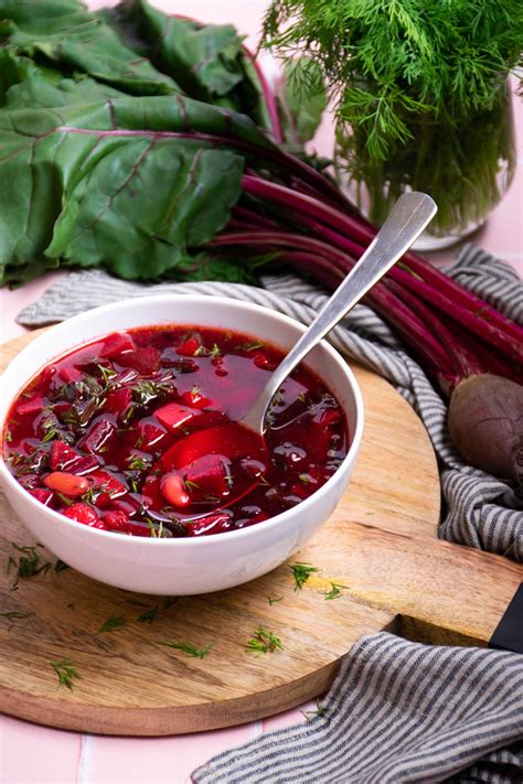 Thematic photo of fresh beetroots with leaves and a bowl of beetroot soup