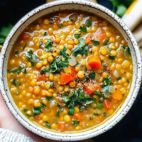 Thematic photo of a cozy bowl of lentil soup with potatoes and spices on a wooden table, possibly with steam rising