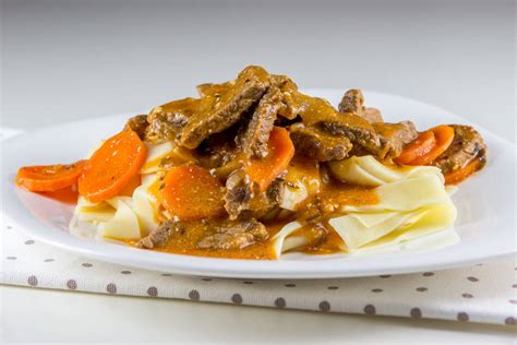 Tematska fotografija kuhane govedine v kremni omaki z zelenjavo in prilogo