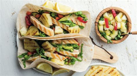 Pripravljeni tacosi s piščančjim in zelenjavnim nadevom, posuti z naribanim sirom.