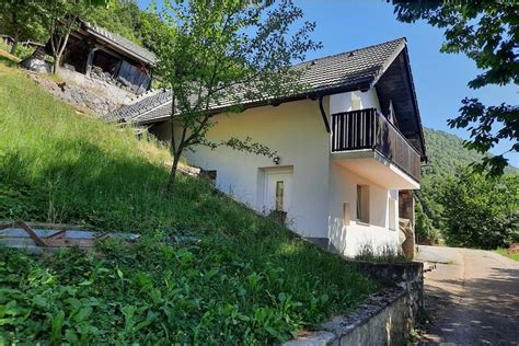 Zunanji posnetek Hiše Fink v Irči vasi z zelenjem in reko Krko v ozadju