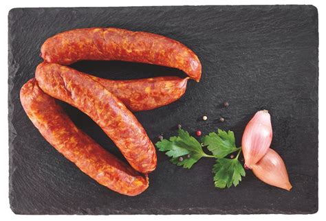 Prikaz različnih vrst tradicionalnih slovenskih klobas na leseni podlagi