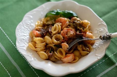 Tematična fotografija krožnika orecchiette z lignji, koromačem in paradižnikom, posuto s svežimi zelišči.