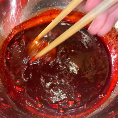 The process of marinating chicken with Char Siu red marinade in a bowl