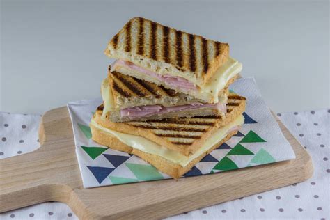 Prikaz sestavin za pripravo toasta: kruh, sir, šunka, jajca in zelenjava na kuhinjski mizi