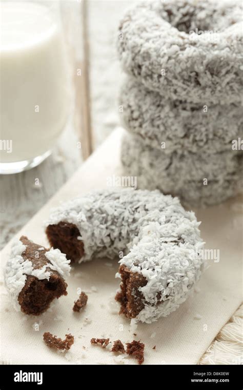 Close-up photo of a freshly fried doughnut dipped in chocolate and covered with coconut flakes.