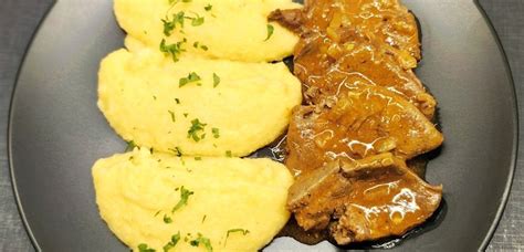 Prikaz končane jedi iz piščančje drobovine v omaki, postrežene s polento.