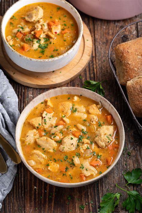 Fotografija piščančje obare z zelenjavo in zdrobovimi žličniki v globokem krožniku.