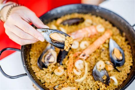 Tematska fotografija: Sveže pripravljena paella v veliki ponvi, polna morskih sadežev in zelenjave.