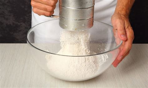 Close-up photo of flour being sifted into a bowl with other dry ingredients