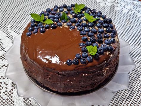 Končana dvojna čokoladna torta z lešniki in ganache prelivom, okrašena s čokoladnimi dodatki