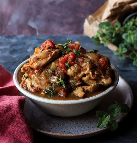 Thematic photo of a rustic chicken stew being served in a bowl with fresh herbs