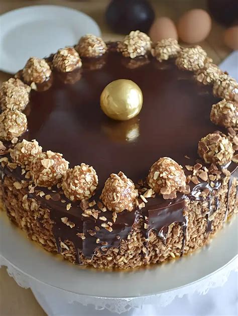 Fotografija okusne Ferrero Rocher torte s čokoladnim prelivom in celimi lešniki na vrhu.
