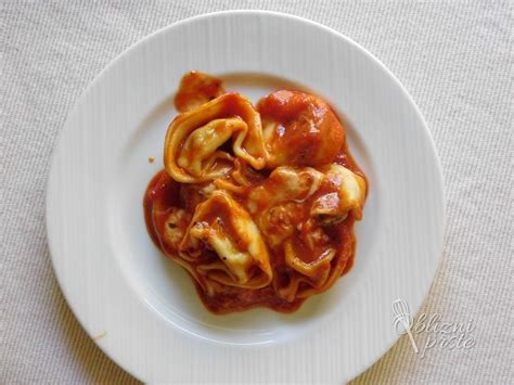 postreženi tortelini v paradižnikovi omaki s pestom in naribanim sirom