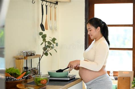 Thematic photo of a pregnant woman preparing healthy food in the kitchen