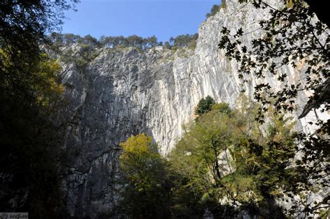 Pogled na skalnato steno s prehodi, skozi katero se prebijajo pohodniki
