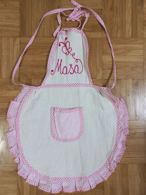 Slikovni prikaz personaliziranega predpasnika z izvezenim imenom na žepu.