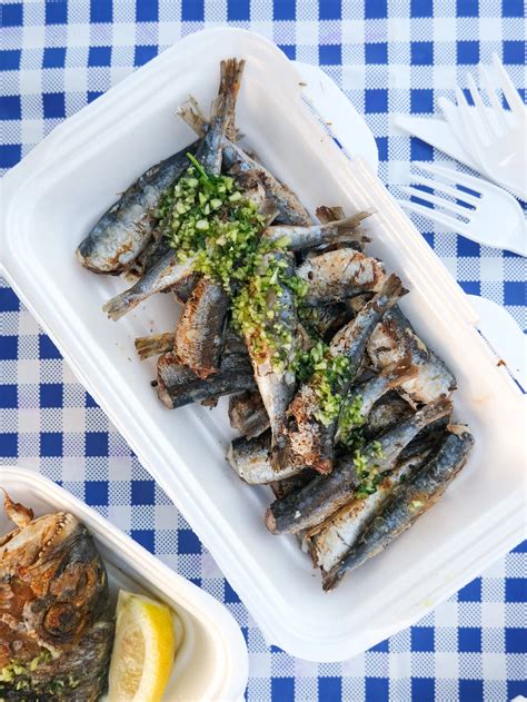Sveže pečene sardine na žaru, postrežene s skledico tržaške omake in kruhom.