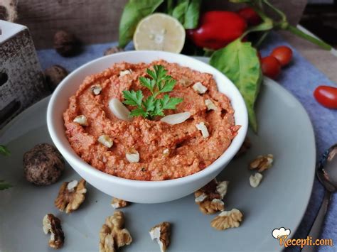 Posuda sa kremastim namazom od pečenih paprika i oraha, ukrašena orasima i listićem peršuna.