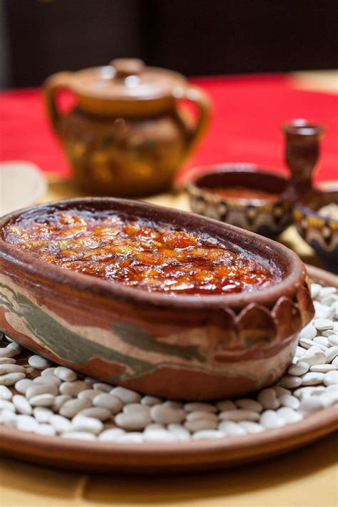Fotografija tradicionalnega srbskega pasulja v glineni posodi, postreženega s svežim kruhom.