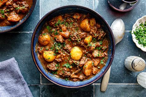 Tematska fotografija: bograč, ki se kuha v kotlu na stojalu nad odprtim ognjem, z dimom v ozadju