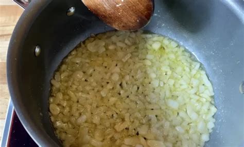 Sautéing chopped onions and garlic in a pot with olive oil