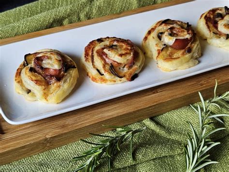 Pravokotnik testa, obložen s pršutom, olivami in parmezanom, pripravljen za zvijanje