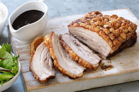 Photo of a perfectly roasted pork belly with crispy skin, served on a plate