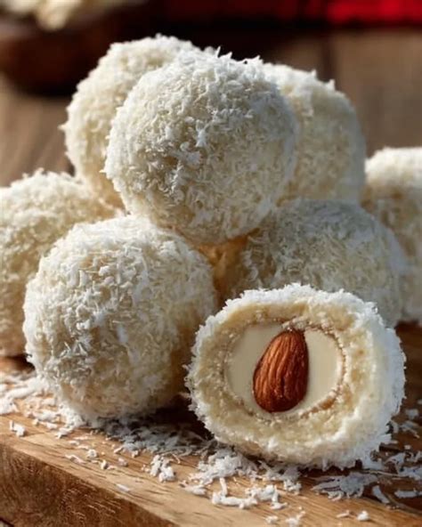 Fotografija zdravih Raffaello kroglic, posutih s kokosom, z eno kroglico prerezano
