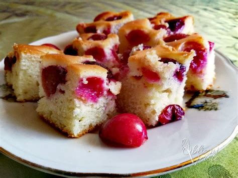 Fotografija sočnega skutinega peciva s svežimi češnjami, narezanega na kocke