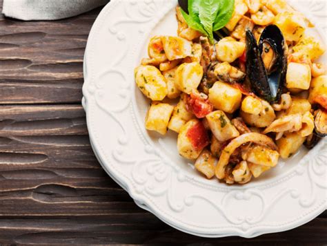 fotografija sveže pečene pice z morskimi sadeži, bogato obložene s školjkami, lignji in kozicami