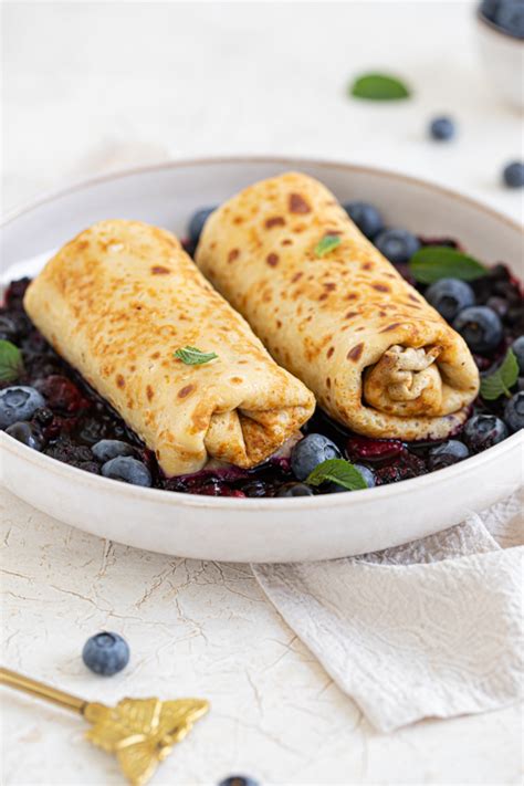 Prikaz razvlečenega testa, pripravljenega za polnjenje s skutnim nadevom in borovnicami.