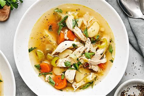 Thematic photo of chicken soup ingredients (chicken, root vegetables, herbs)