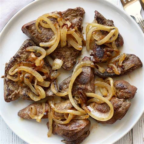 Thematic photo of a plate of cooked veal liver with onions and a side dish