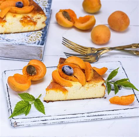 Thematic photo of a slice of cottage cheese apricot pie on a plate, with fresh apricots in the background.
