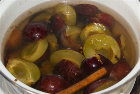 Slivov kompot serviran v skodelici z žlico in cimetovo palčko