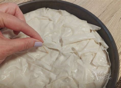 Shema prikazuje postopek razvlačenja vlečenega testa na prtu.