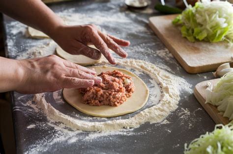 Hands shaping a dumpling with an apricot filling.