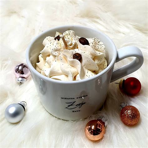 slika snežaka iz bele čokolade, ki se topi v skodelici vroče čokolade z lešniki in penicami