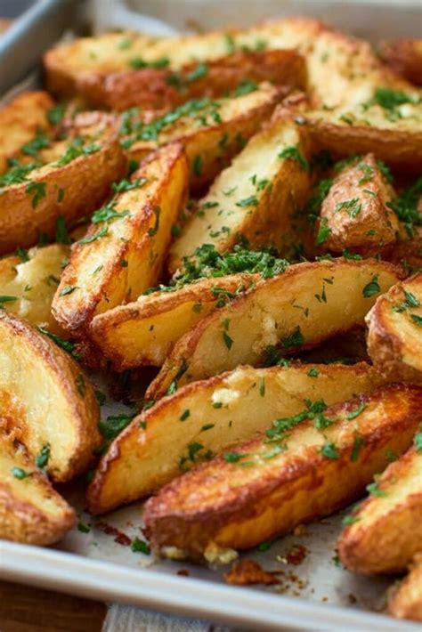 Close-up photo of perfectly roasted potato wedges with herbs and garlic, fresh out of the oven.