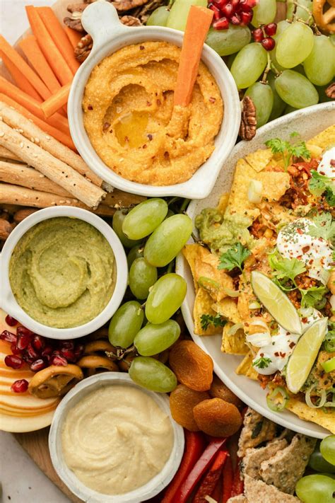 Različna zelenjava narezana na palčke, ob skodelicah z veganskimi namazi