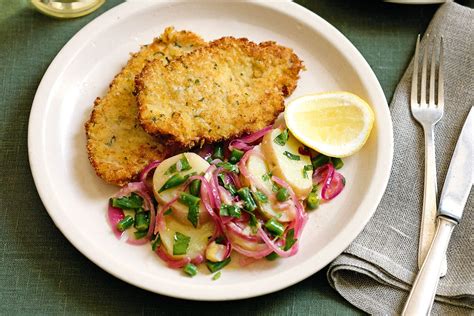 Photo of grilled pork schnitzel with various side dishes like roasted potatoes and vegetables