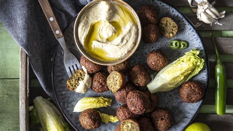 Pester izbor jedi iz menija Abi Falafel, vključno s falafli, humusom in mesnimi jedmi
