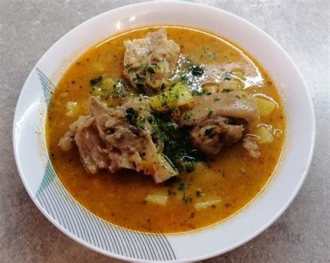 Fotografija svinjskih nogic, korenčka, krompirja in začimb, pripravljenih za juho