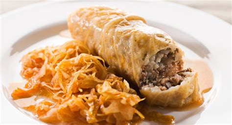 sloji kislega zelja, riža, mletega mesa in klobase v pekaču, pripravljeni za peko