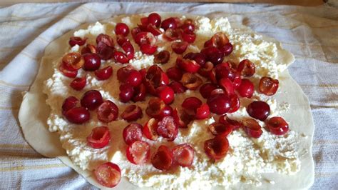 Pripravljen češnjev zavitek s skuto na pekaču, ki čaka na peko.