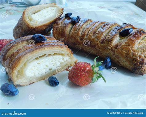 Thematic photo of a warm slice of cottage cheese strudel with berries, next to a cup of coffee