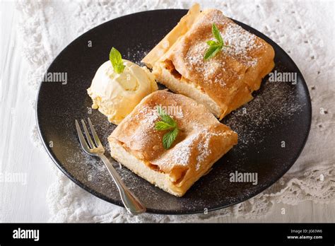 A piece of cottage cheese strudel on a plate with a scoop of vanilla ice cream.
